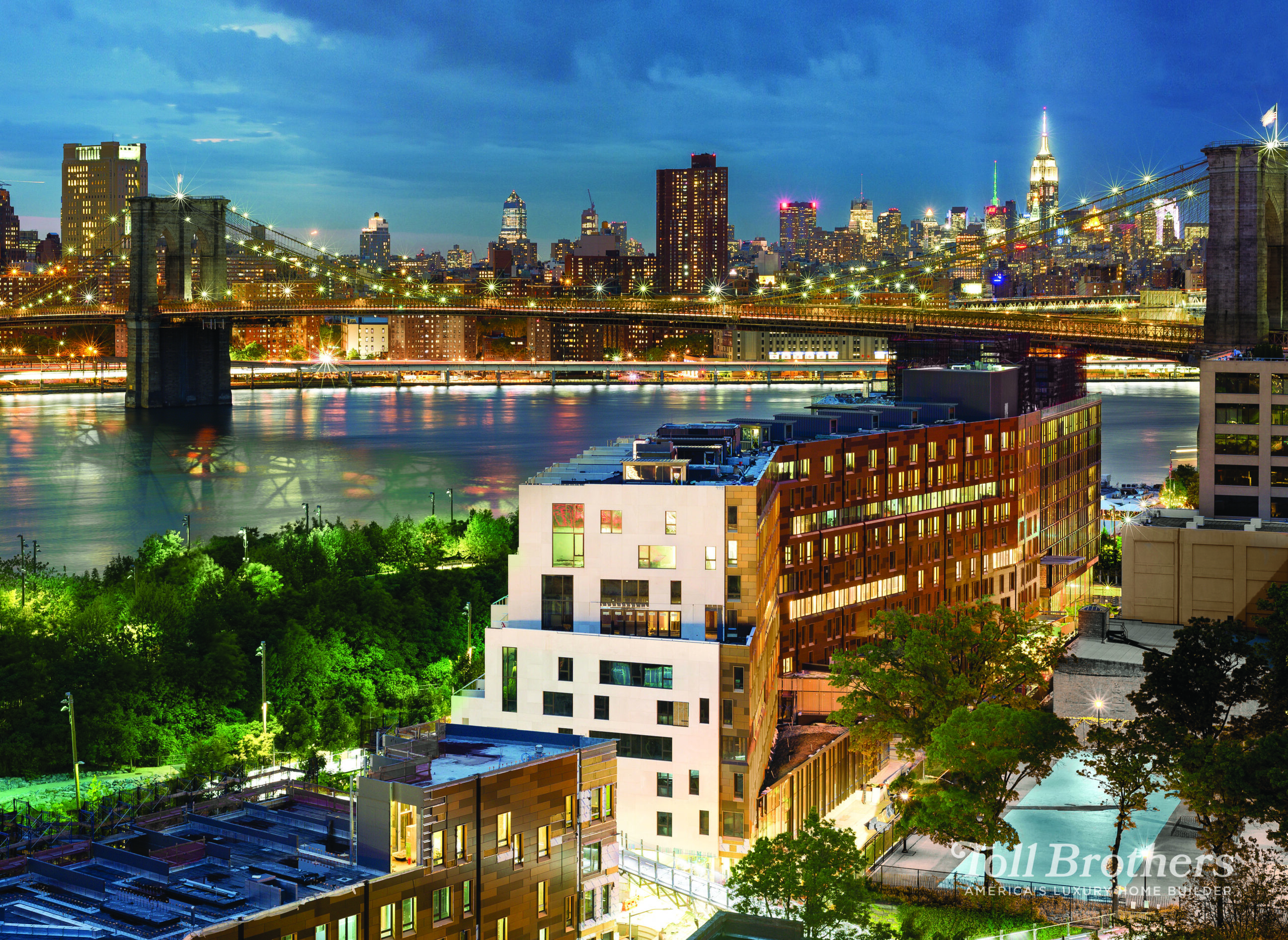 A blue hour  with shining city lights featuring the Pierhouse development with the Brooklyn Bridge and Brooklyn Bridge Park in the background.